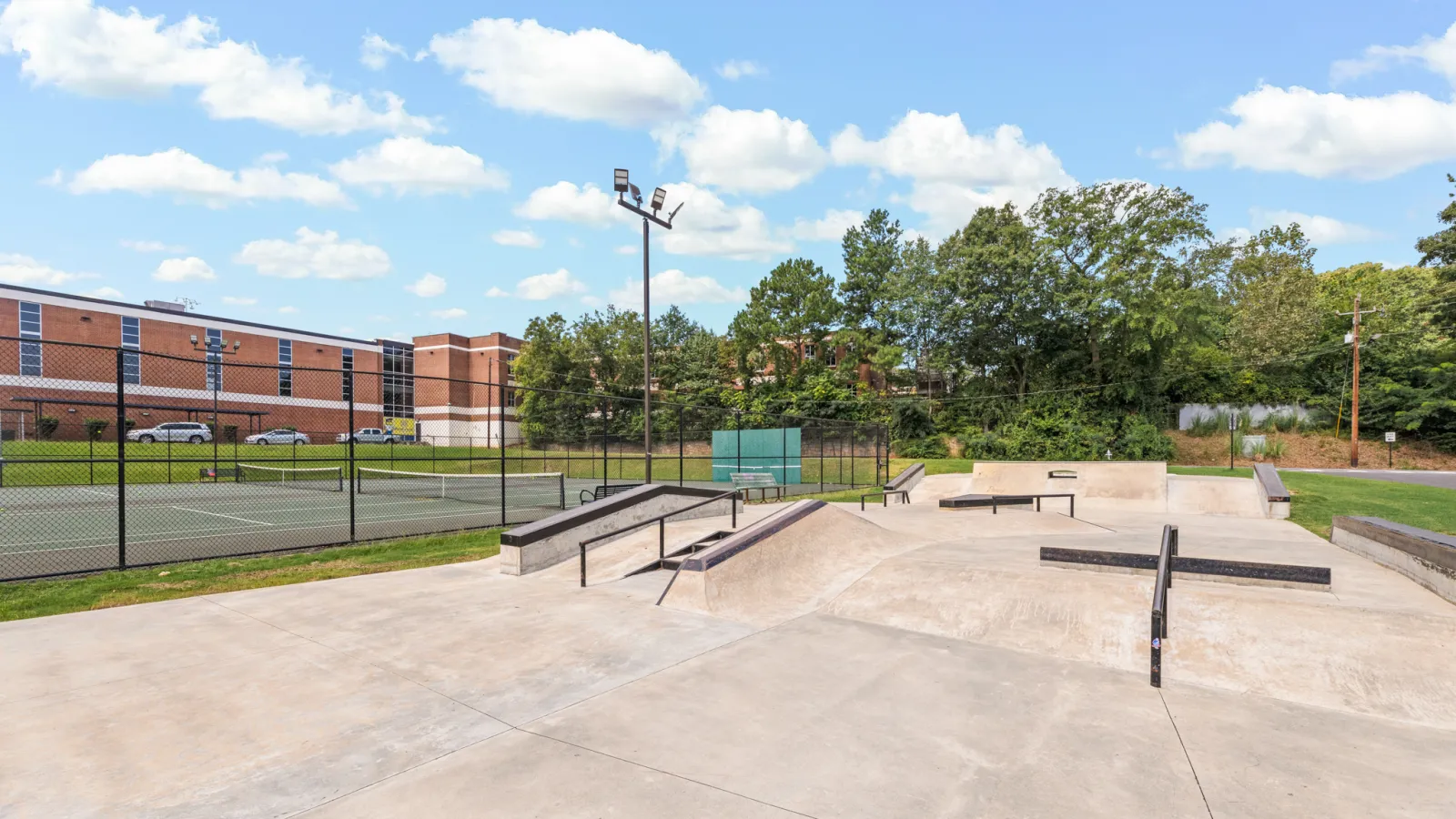 a concrete area with a fence and trees in the background