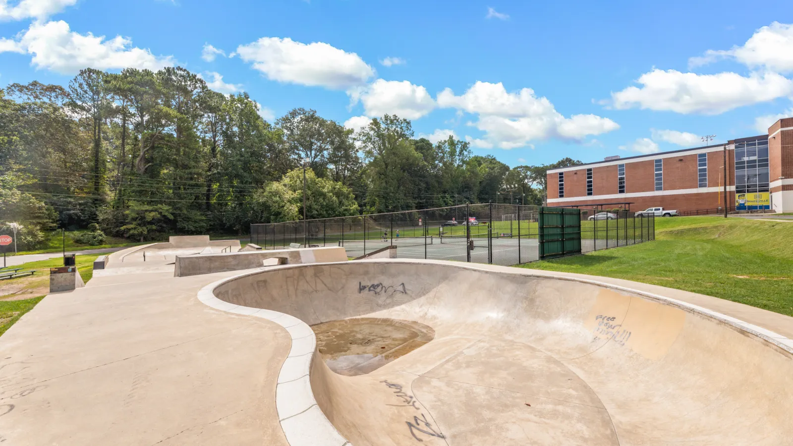 a skate park with a fence and trees in the background