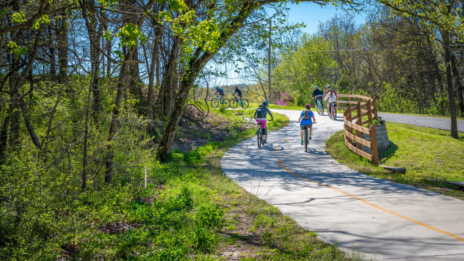 a group of people riding bikes on a path in a park