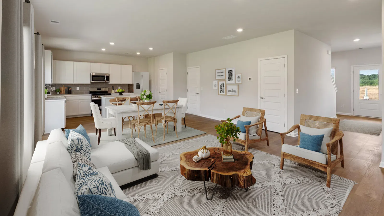 Open-concept living and dining area with modern white kitchen, wood furniture, and neutral decor in a bright home.