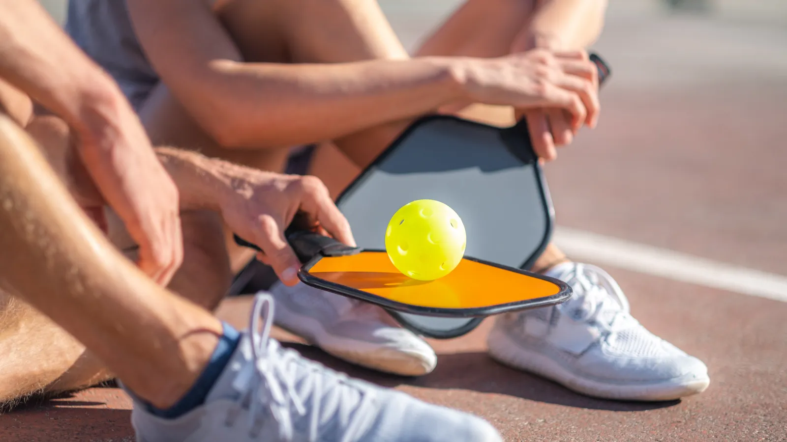 a group of people sitting on the ground with a ball and a tennis racket