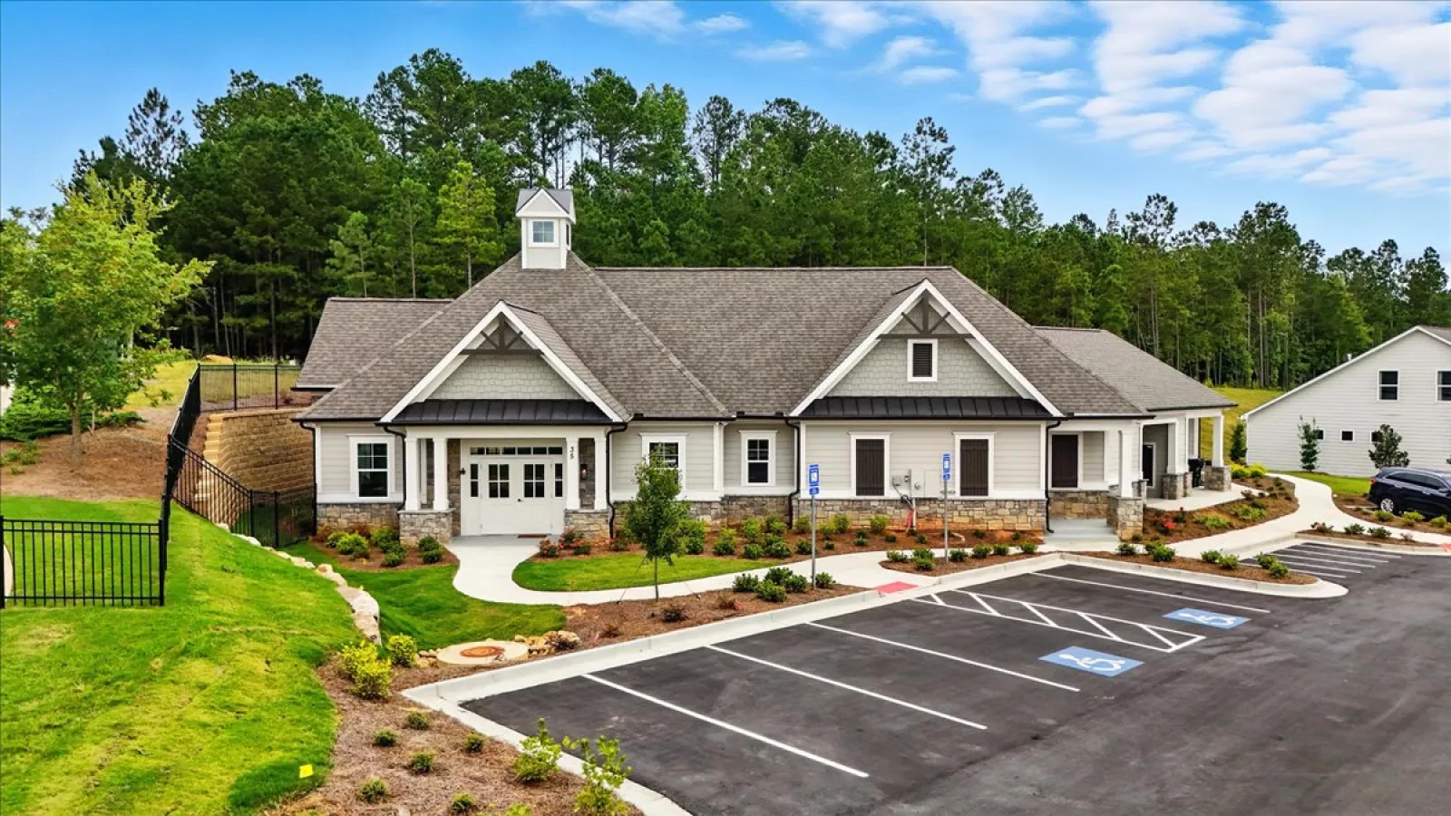 Modern single-story community center with stone accents, surrounded by greenery and ample parking with handicap spaces