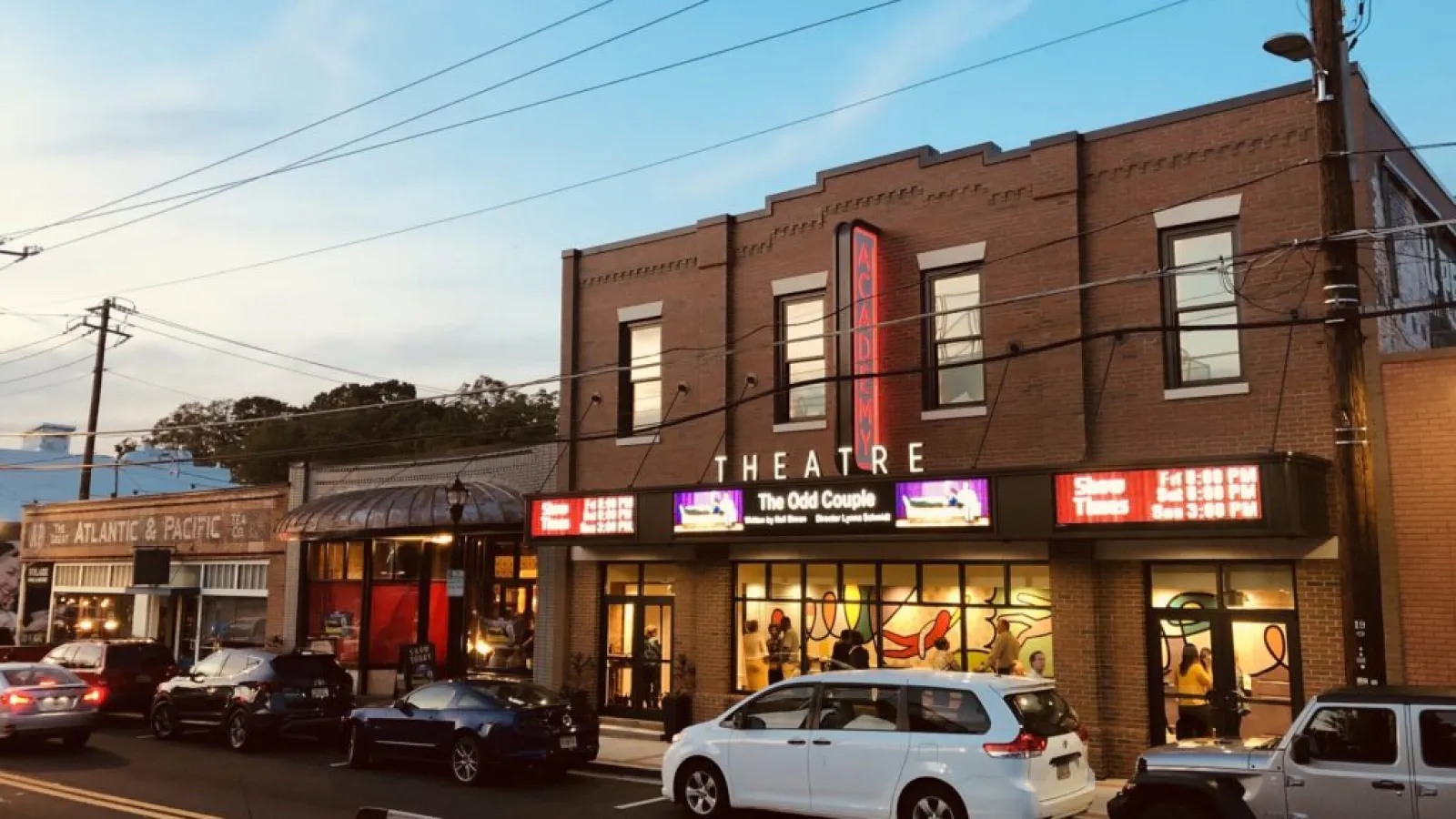 a street with cars parked on the side and a building with a sign