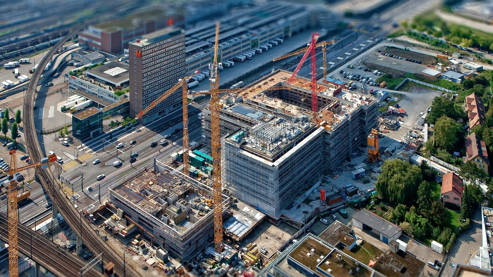 Aerial view of a construction site with cranes and ongoing building developments in an urban area.