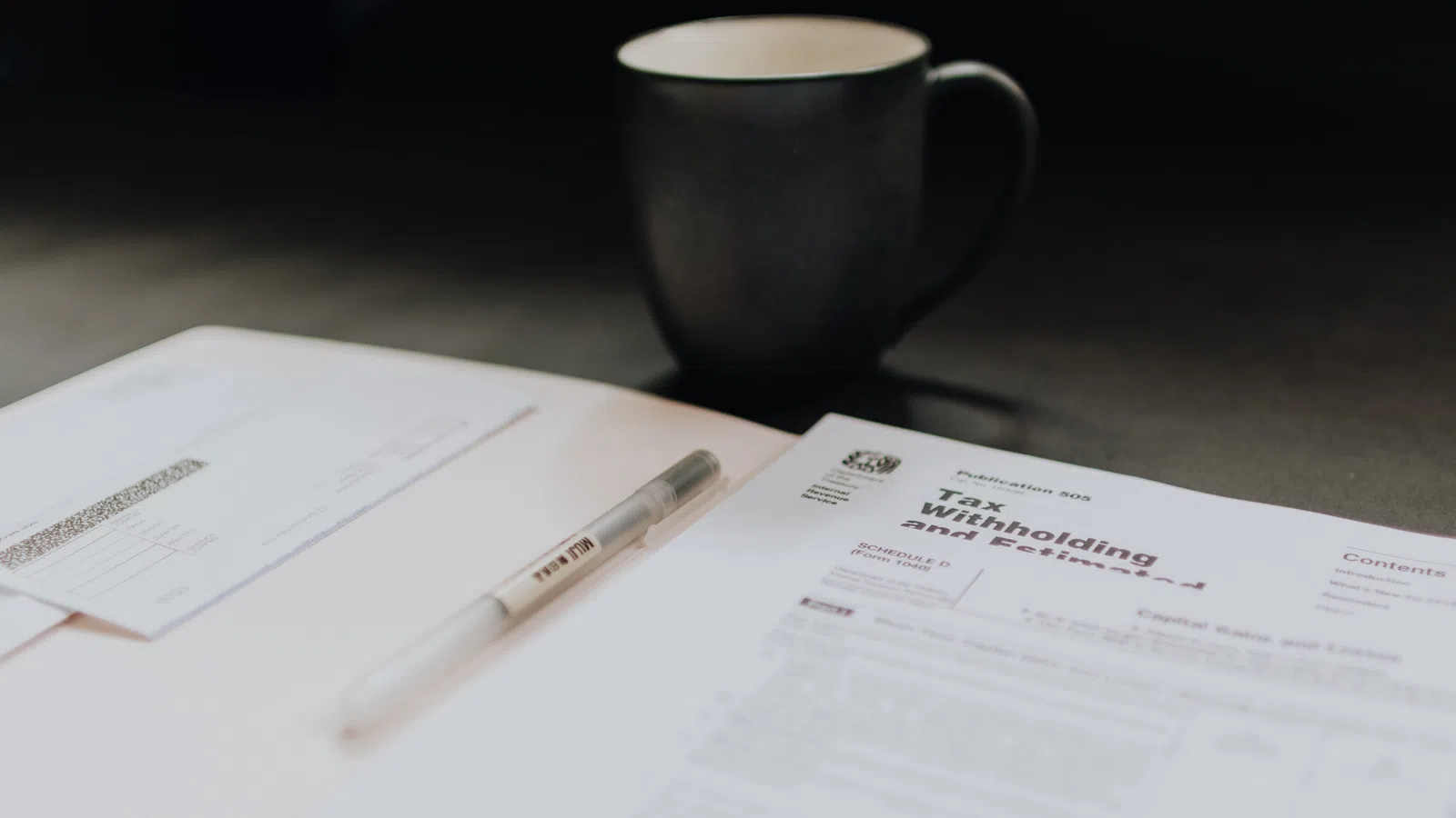 a cup of coffee and a pen on a table