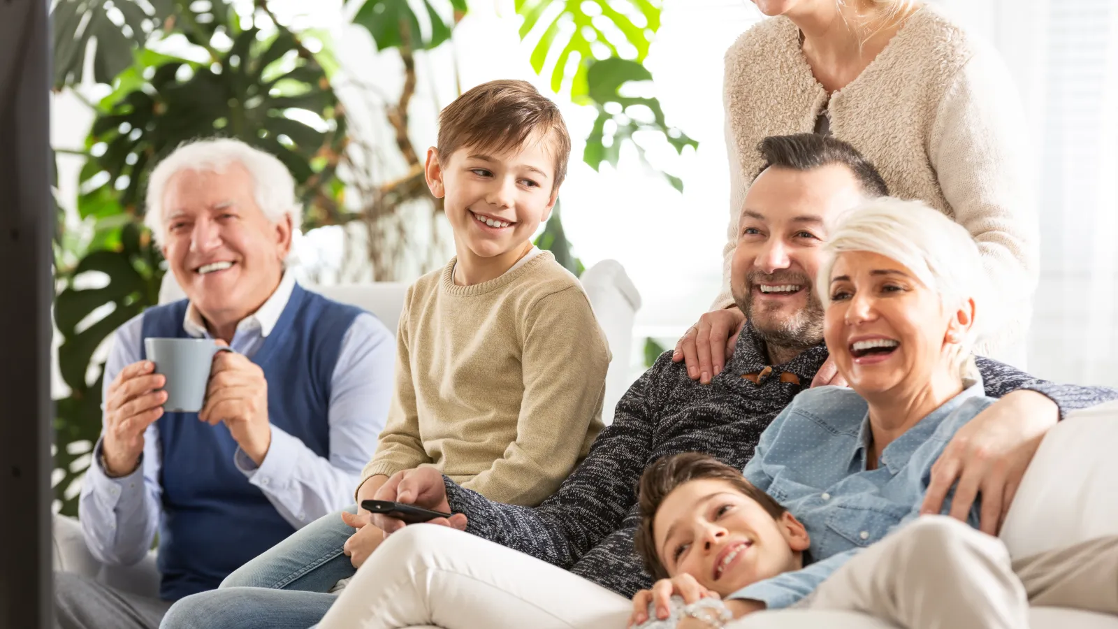 Happy multi-generation family enjoying time together on a couch in a bright living room.