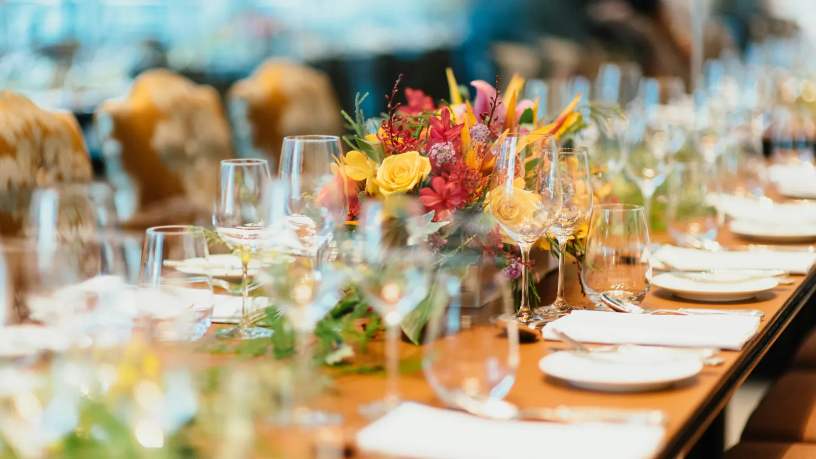 Elegant dining table set with glassware, white napkins, plates, and vibrant floral centerpiece for a formal event
