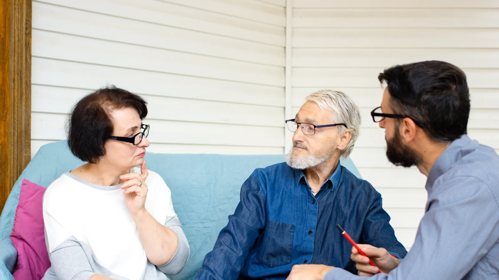 Three adults discussing finances with documents and calculator on table during a meeting at home.