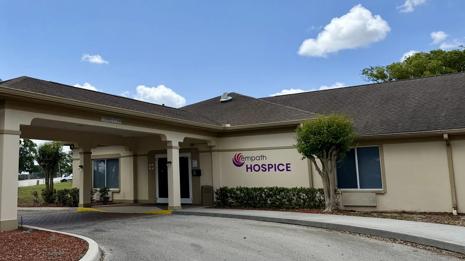 Empath Hospice building exterior with entrance driveway under blue sky and some clouds