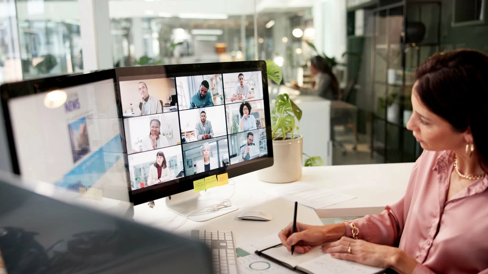 Professional woman attending a video conference with multiple participants on screen.