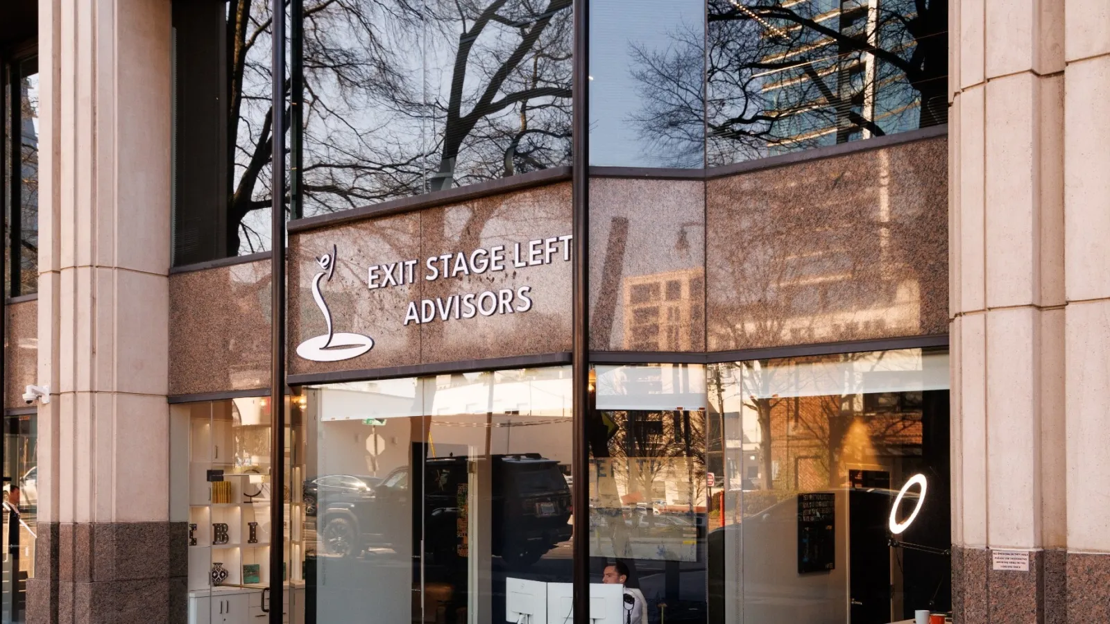 Office exterior of Exit Stage Left Advisors with large glass windows and reflections of nearby buildings.
