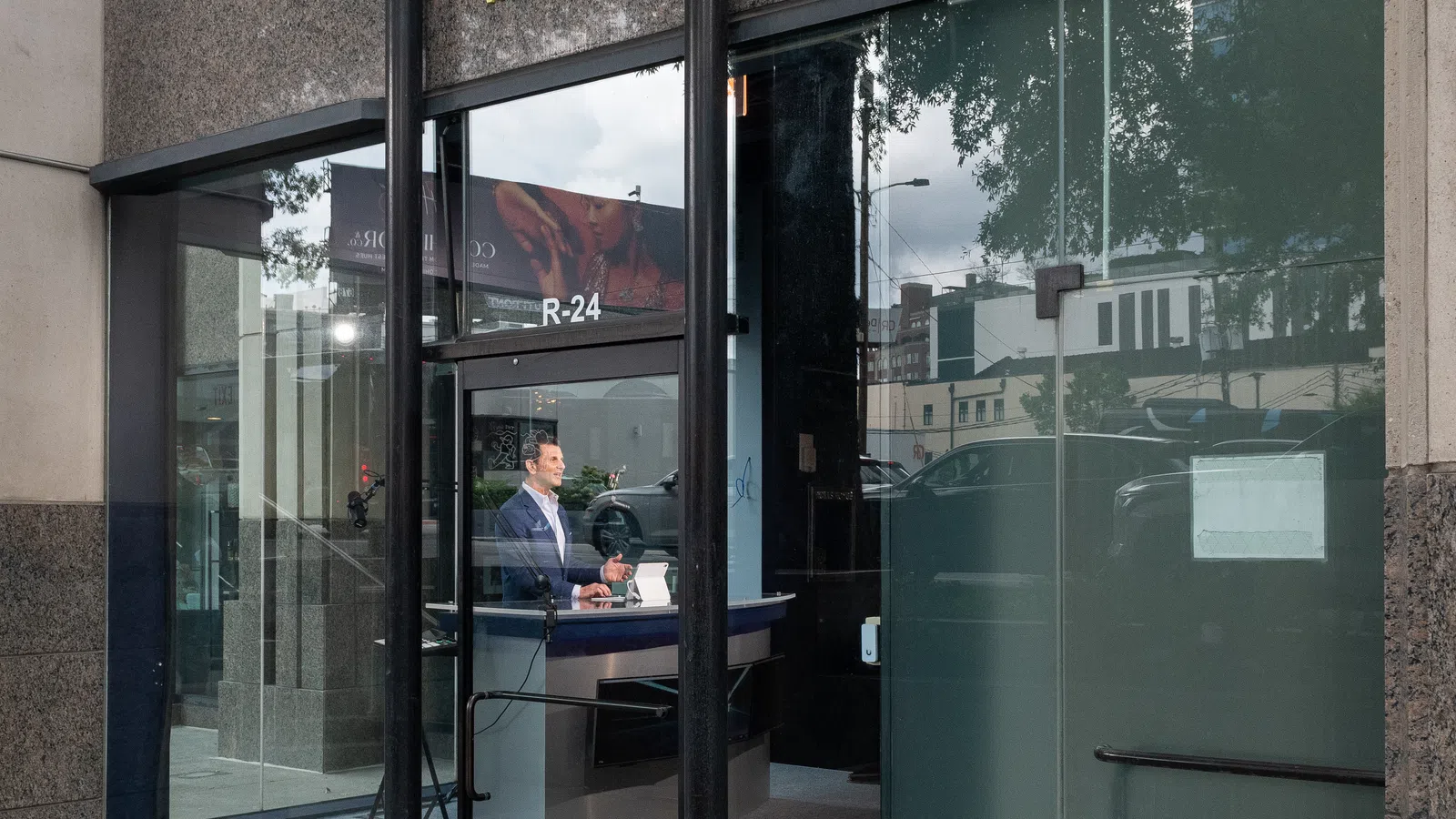 Office entrance of Exit Wealth with glass door, visible receptionist, and city reflections outside.