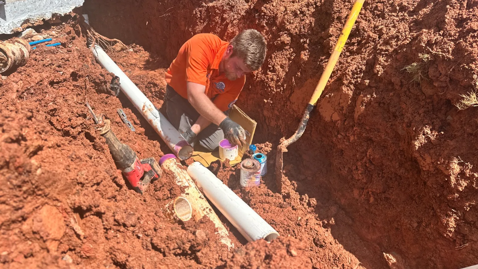 Estes Plumber in an orange shirt installing a new sewer line in atlanta