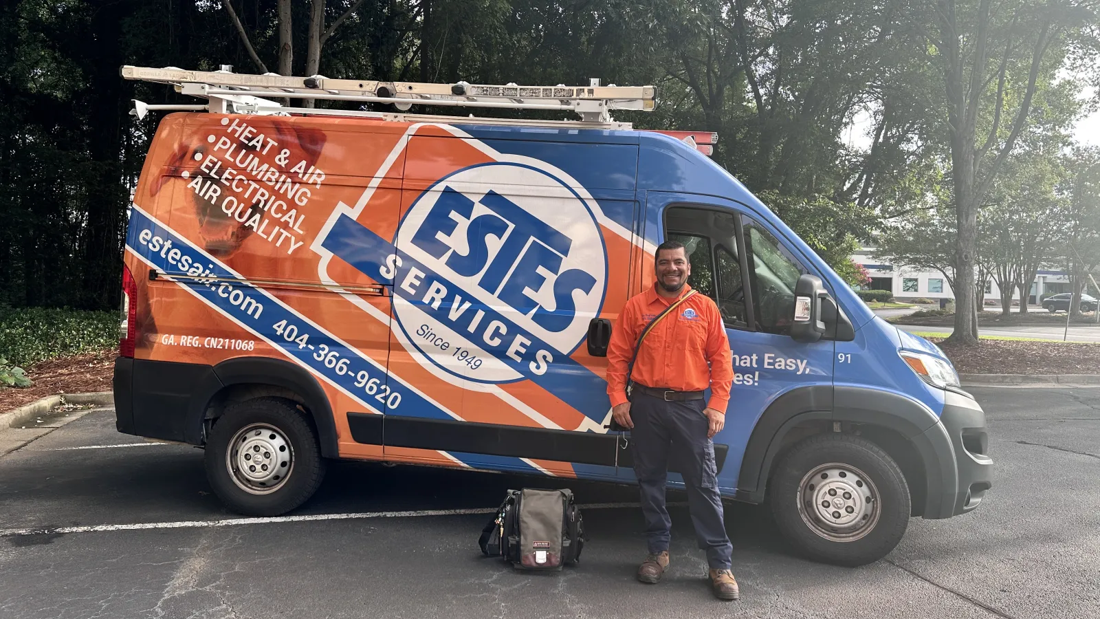 Estes Technician in orange shirt stands beside Estes Services van offering a Georgia HEAR programs.