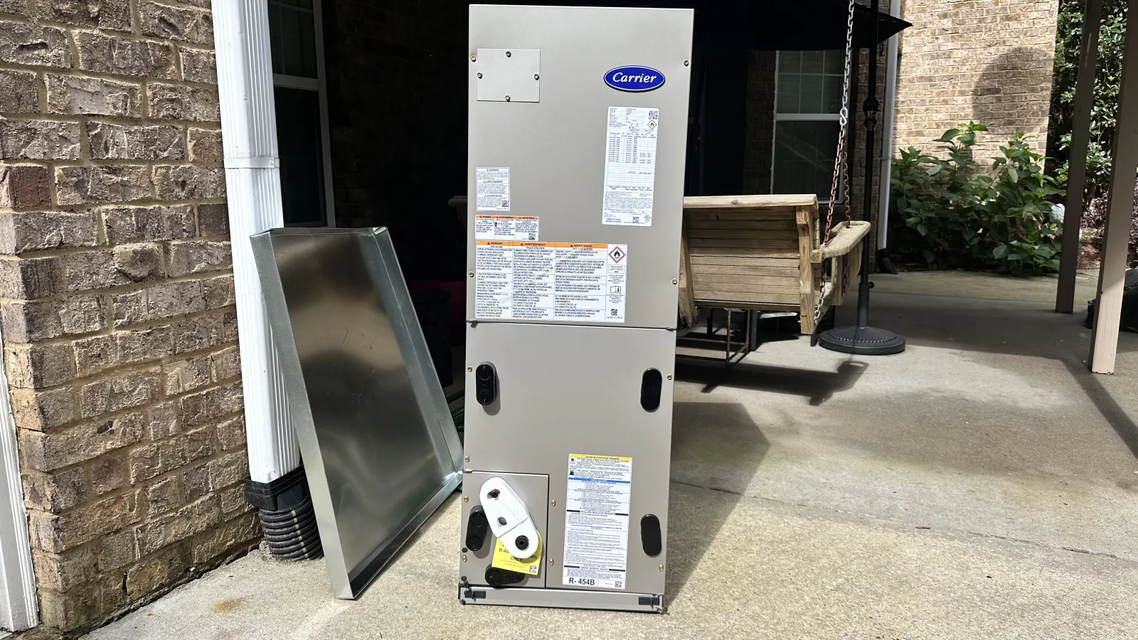 Carrier Air Handler near brick wall and patio swing ready to be installed by Estes HVAC Installers