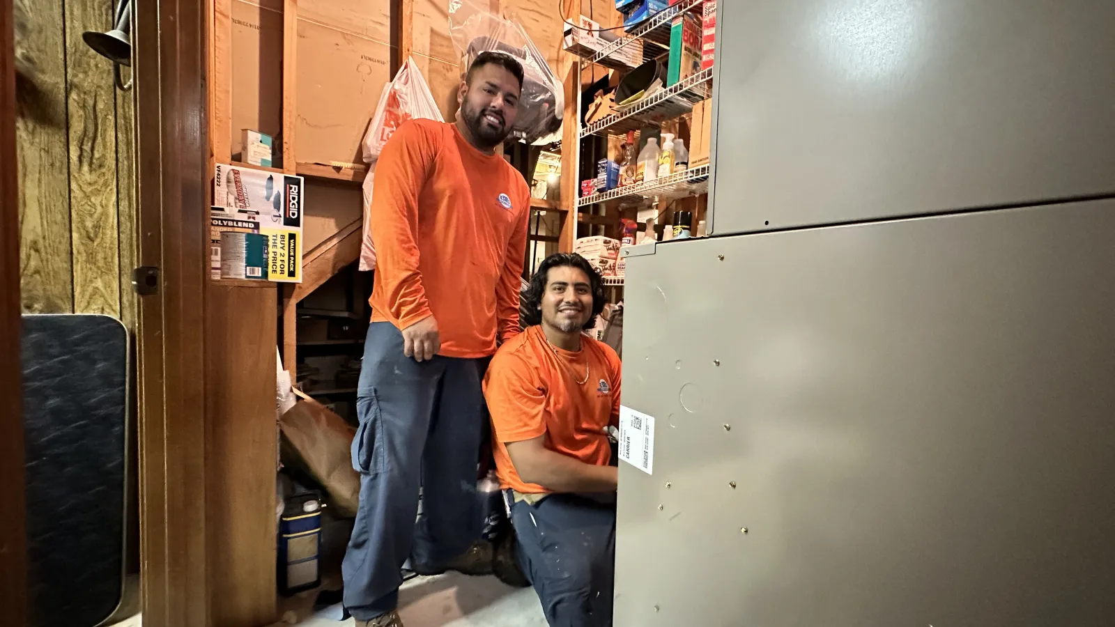 Estes Technicians servicing Split HVAC equipment in a residential utility room filled with tools and supplies.
