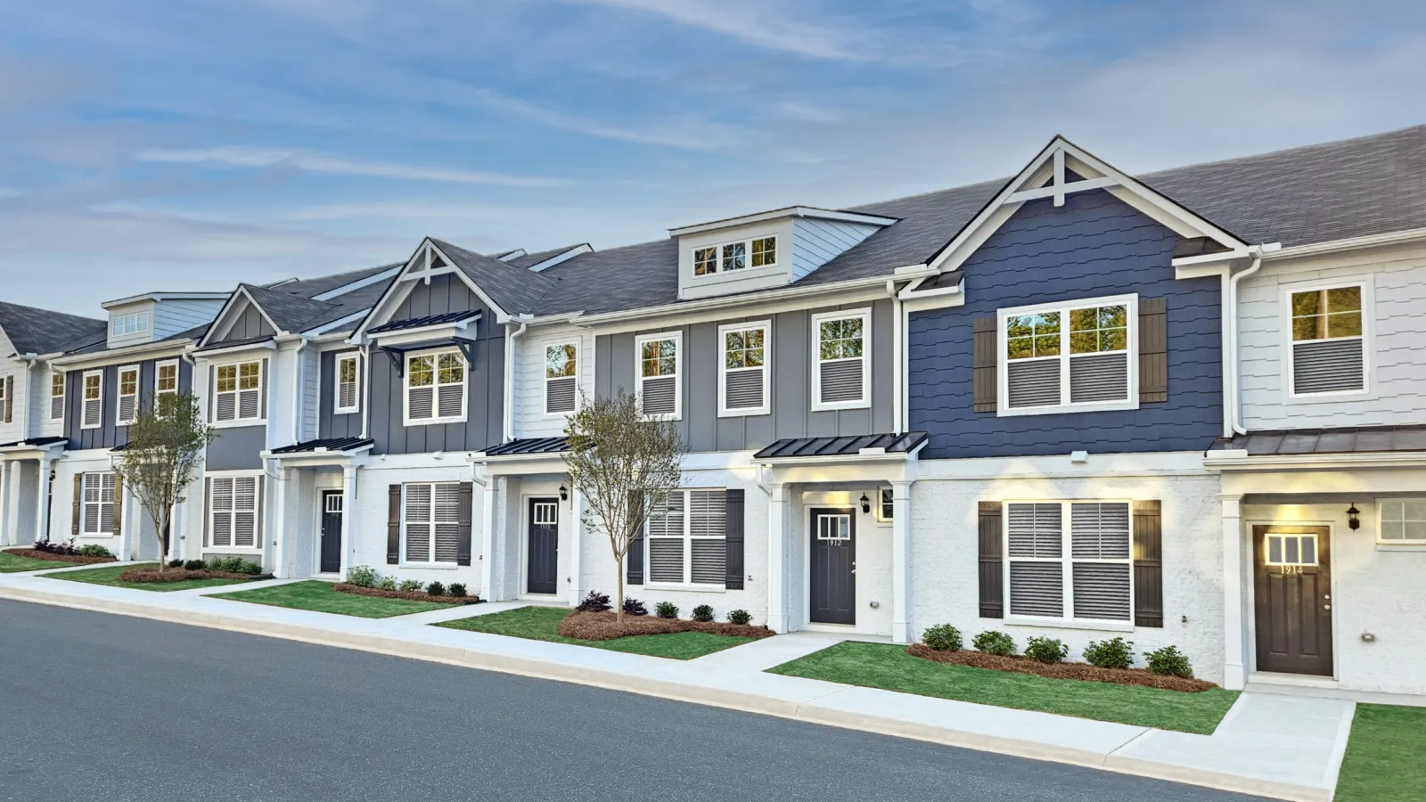 Row of modern two-story townhouses with a mix of gray and white exteriors and landscaped front yards.