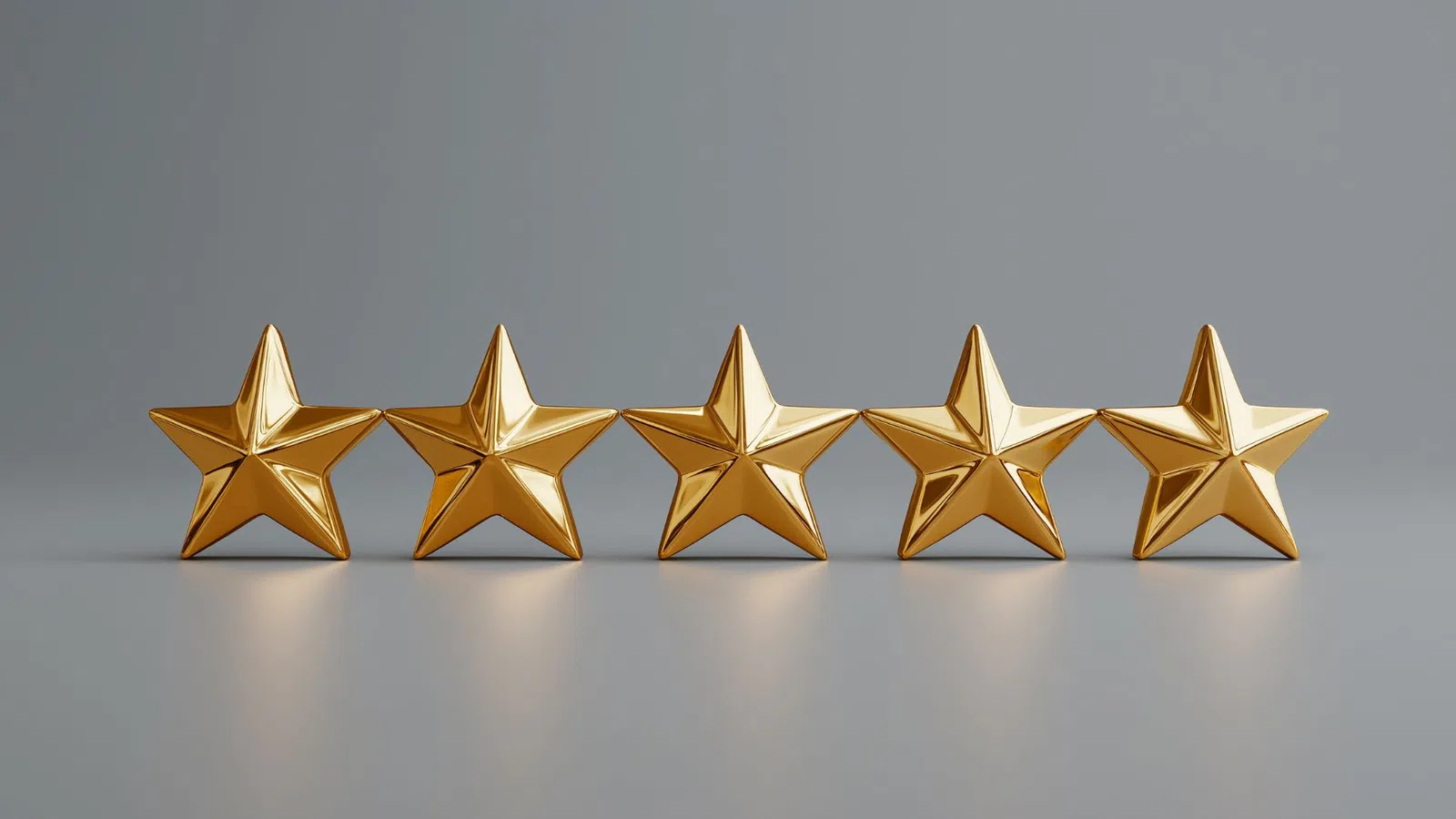 Five shiny gold stars in a row on a smooth gray surface representing five-star rating or quality.