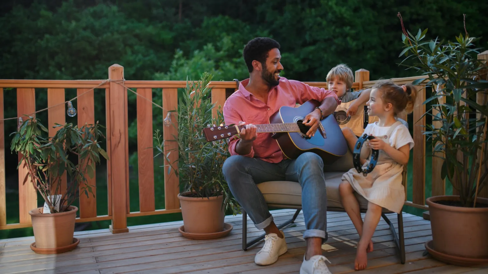 a person playing guitar with a little girl sitting on a chair