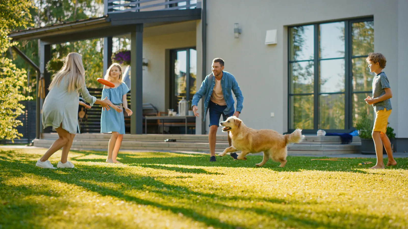 a person and a couple of children playing with a dog in a yard