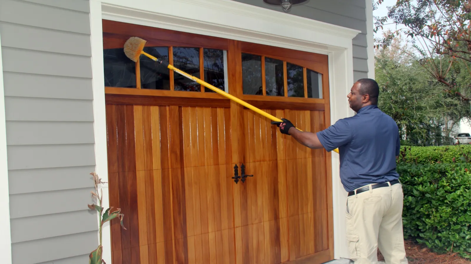 a man holding a broom in front of a wooden door