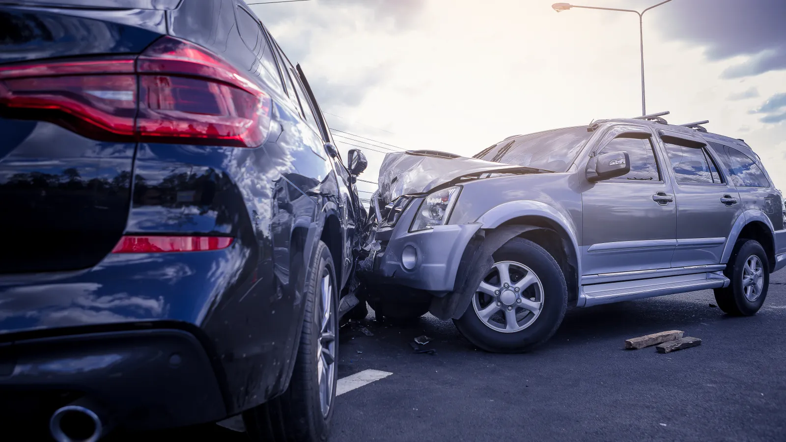 Two SUVs involved in a collision on a road during daylight with visible damage to the front and side.