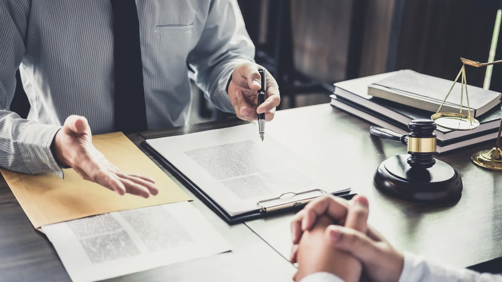 Lawyer explaining legal documents to client at office desk with gavel and legal scales visible