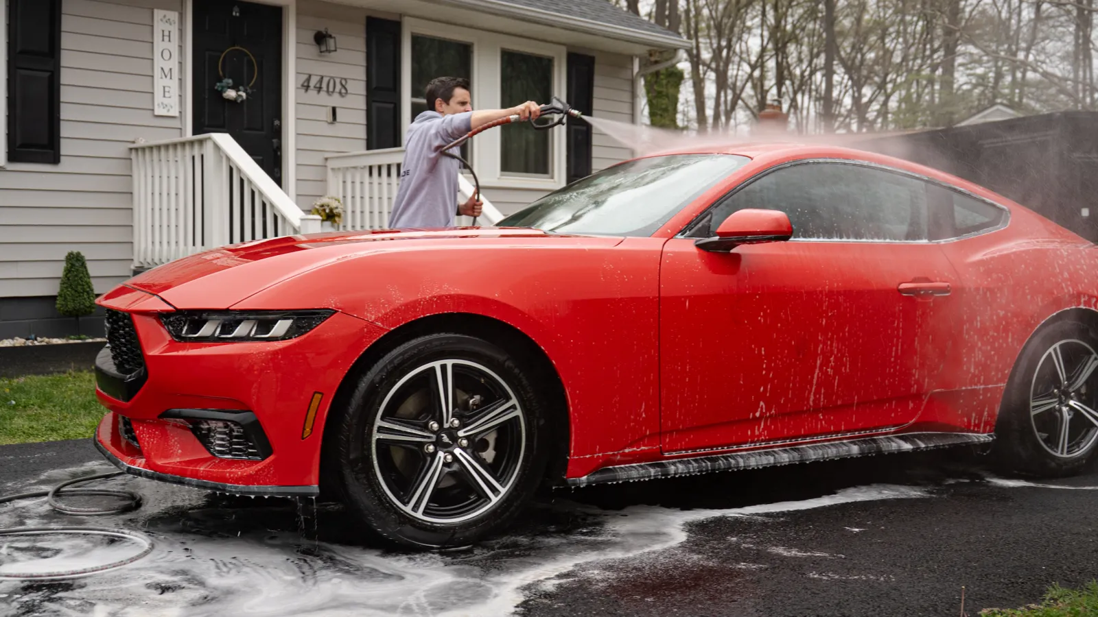 Happy man sitting in a new car, giving thumbs up with a smile in a bright car showroom.