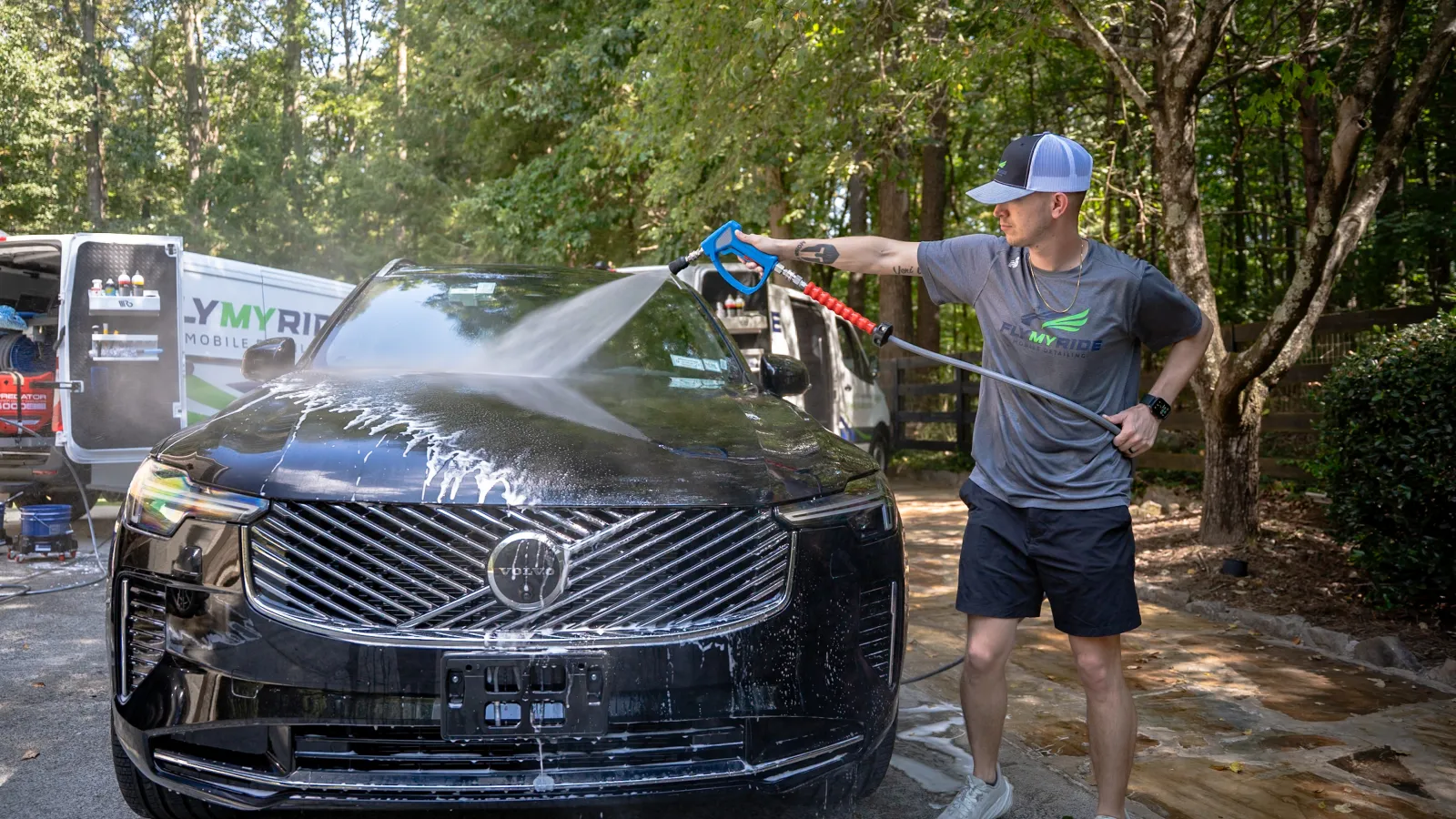Man sitting in car driver's seat smiling as another man leans in from outside the window explaining features.