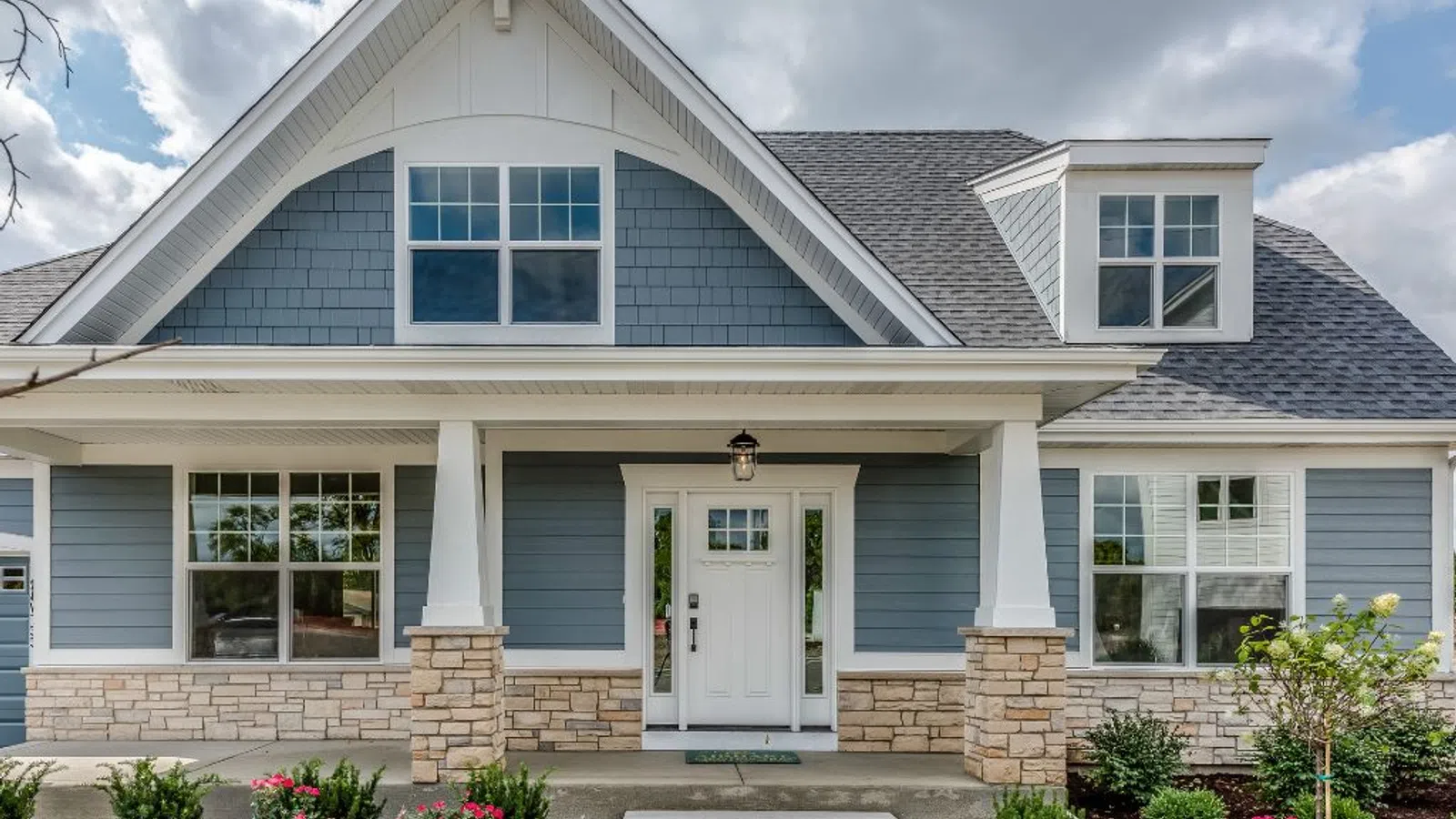 White coastal home with wraparound porch and manicured lawn under clear sky in Braselton, GA