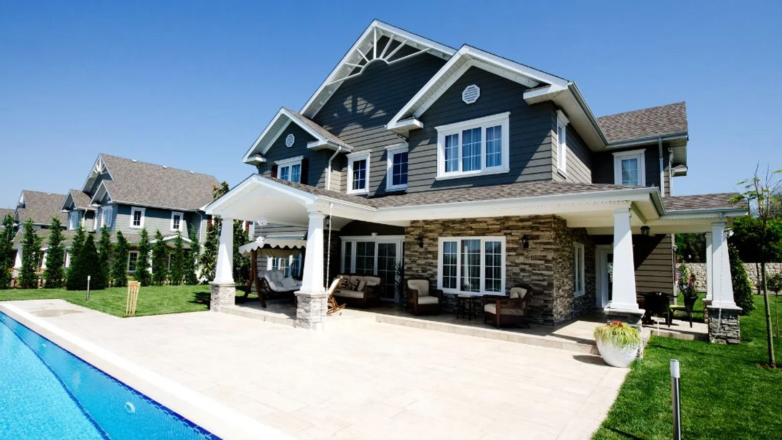 White coastal home with wraparound porch and manicured lawn under clear sky in Coal Mountain, GA