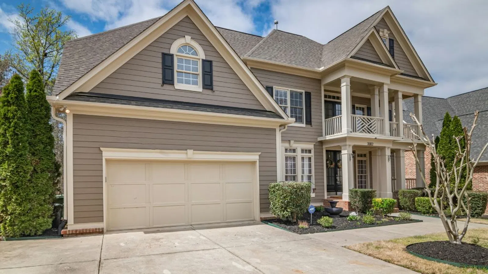 White coastal home with wraparound porch and manicured lawn under clear sky in Smyrna, GA