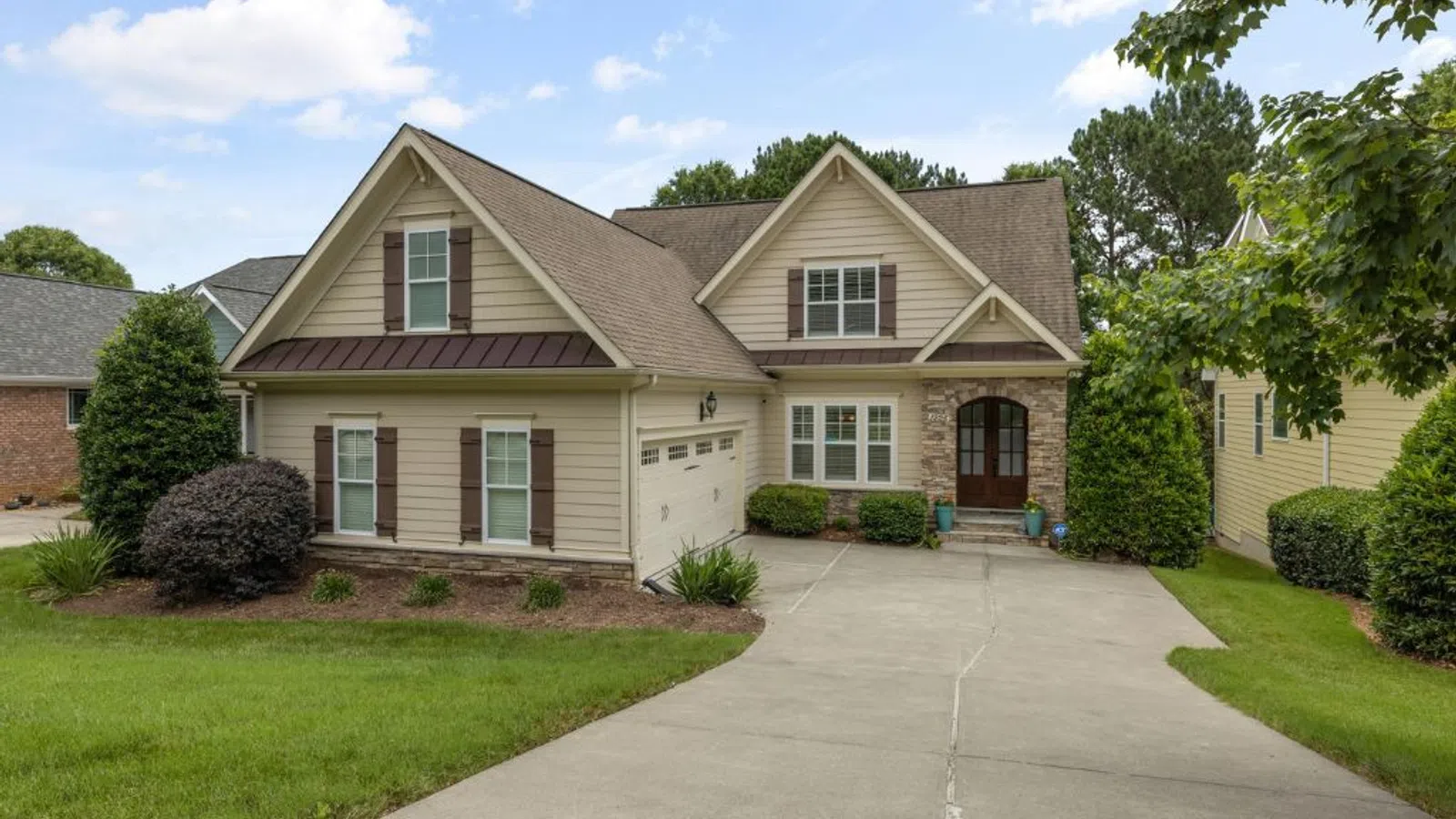 White coastal home with wraparound porch and manicured lawn under clear sky in Roswell, GA