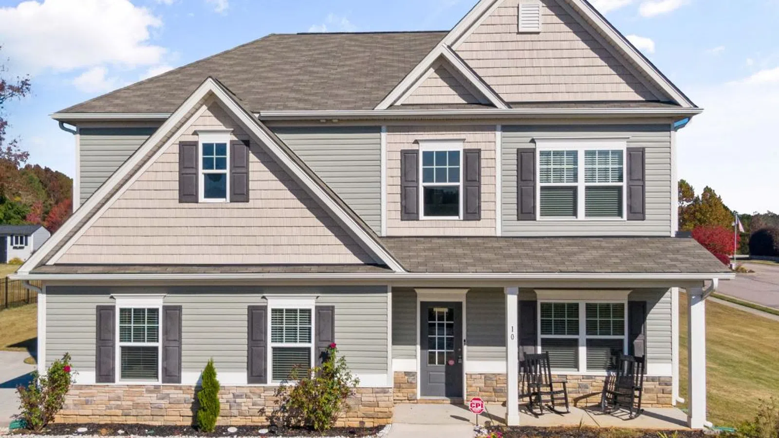 White coastal home with wraparound porch and manicured lawn under clear sky in Sandy Springs