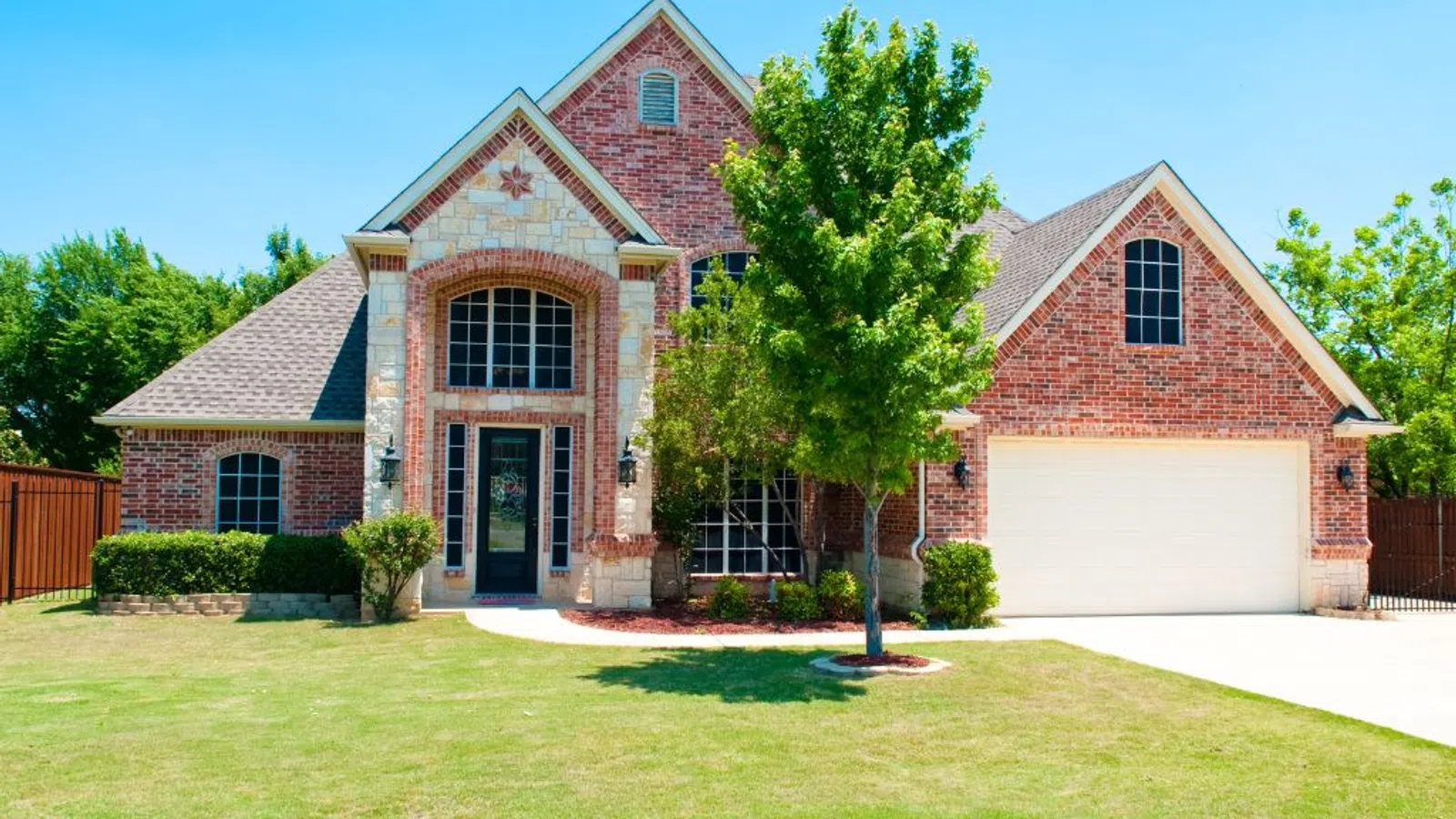 White coastal home with wraparound porch and manicured lawn under clear sky in Dacula, GA