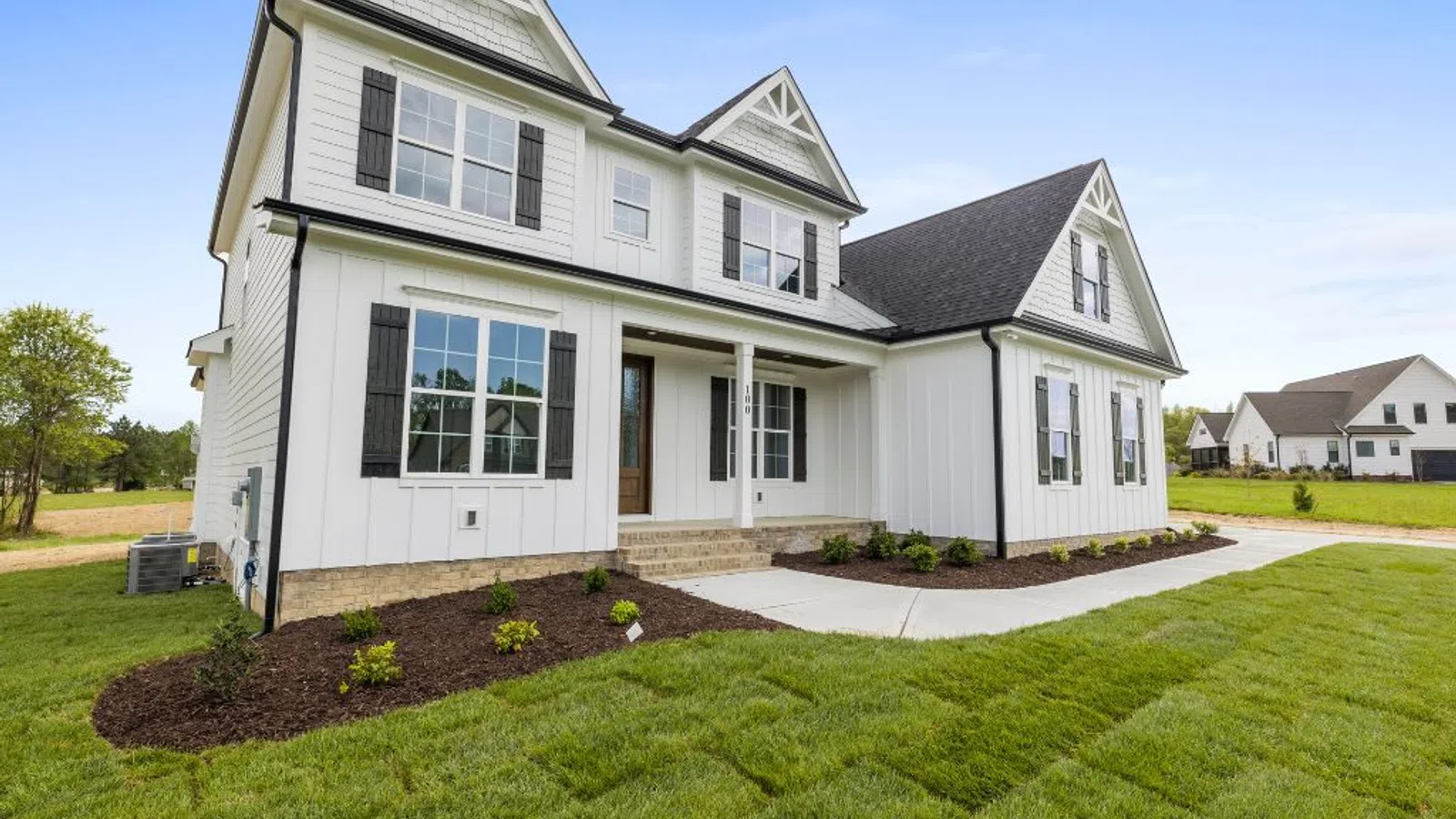 White coastal home with wraparound porch and manicured lawn under clear sky in Marietta, GA