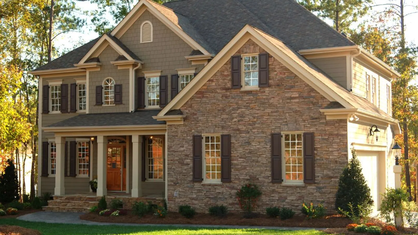 White coastal home with wraparound porch and manicured lawn under clear sky in Brookhaven, GA
