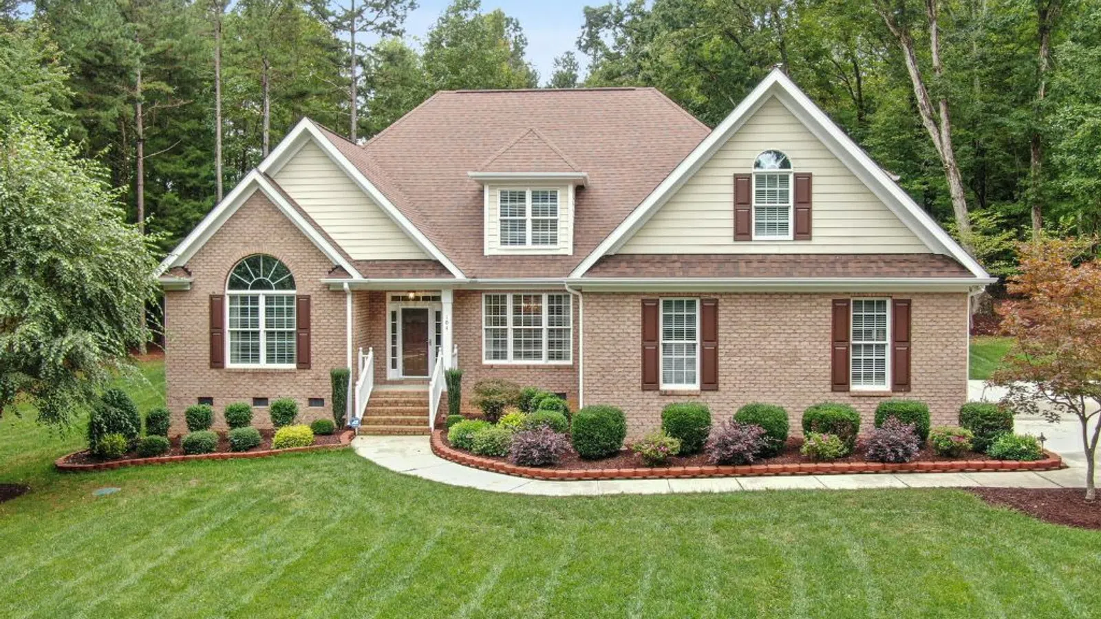 White coastal home with wraparound porch and manicured lawn under clear sky in Milton, GA