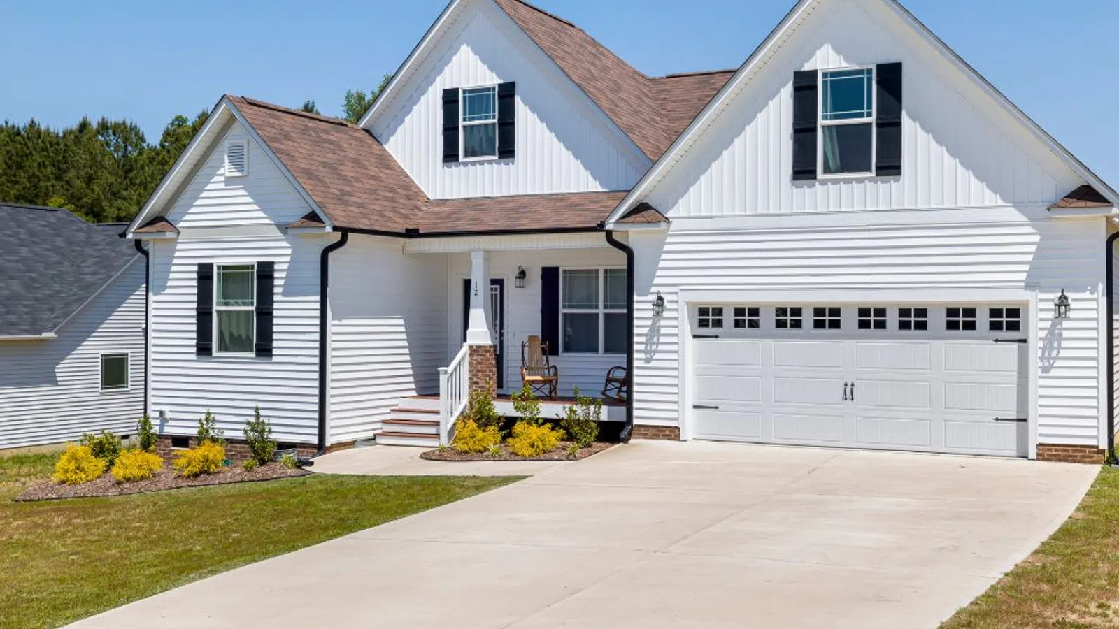 White coastal home with wraparound porch and manicured lawn under clear sky in Lawrenceville, GA