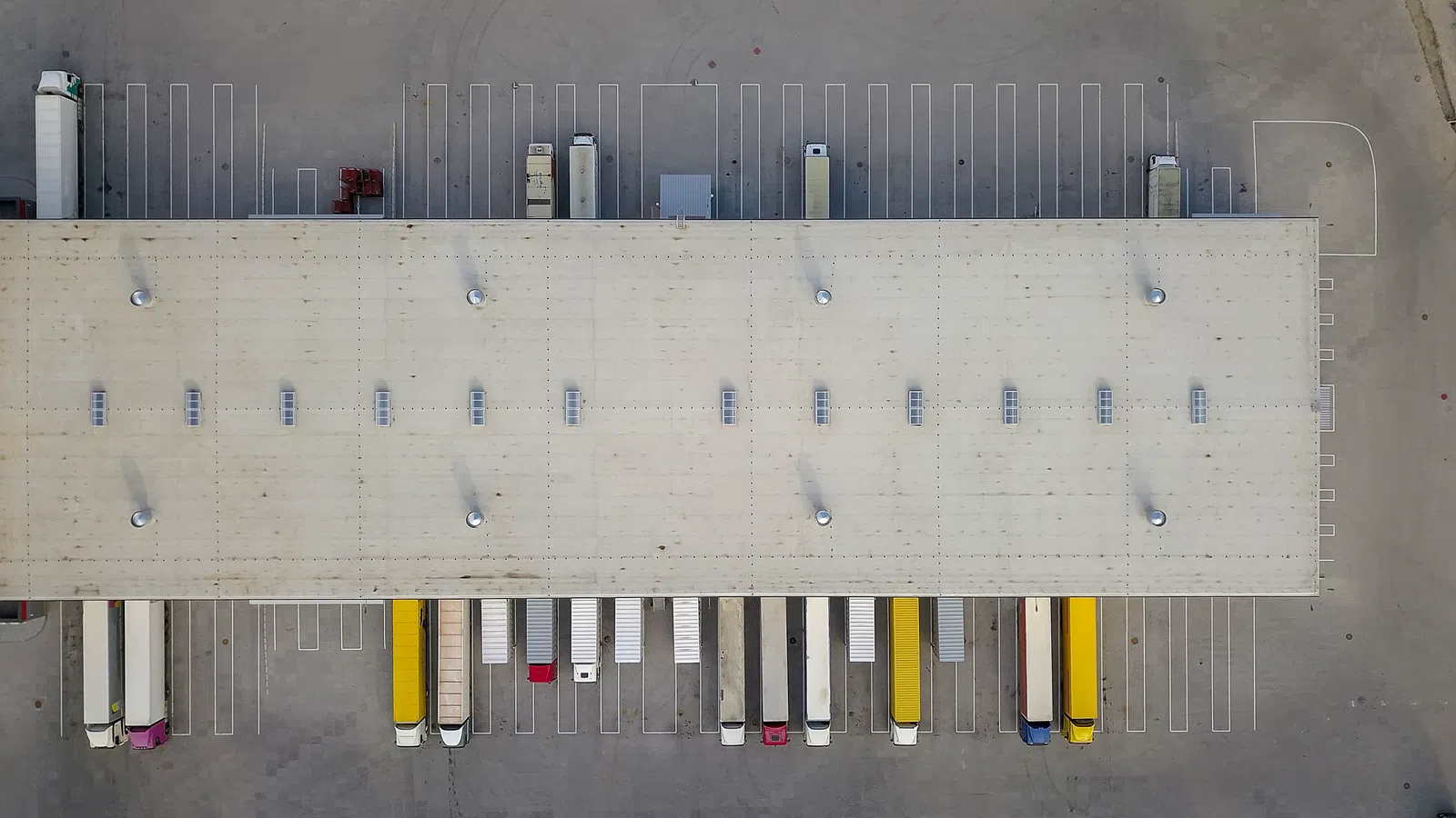 aerial view of large logistics center with several trucks and bays