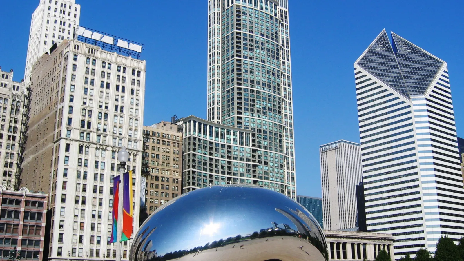 a large reflective sphere in front of a group of tall buildings