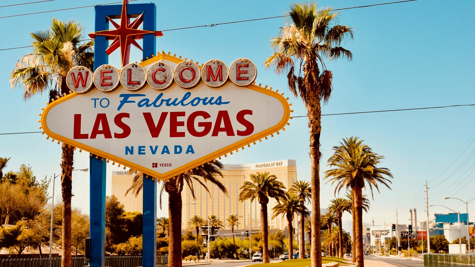 Iconic Welcome to Fabulous Las Vegas Nevada sign with palm trees and clear blue sky in the background.