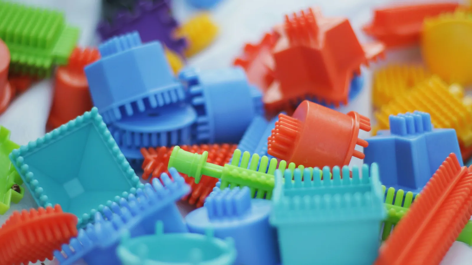 Close-up of colorful plastic construction toy pieces with various shapes and connectors in red, blue, green, and purple.