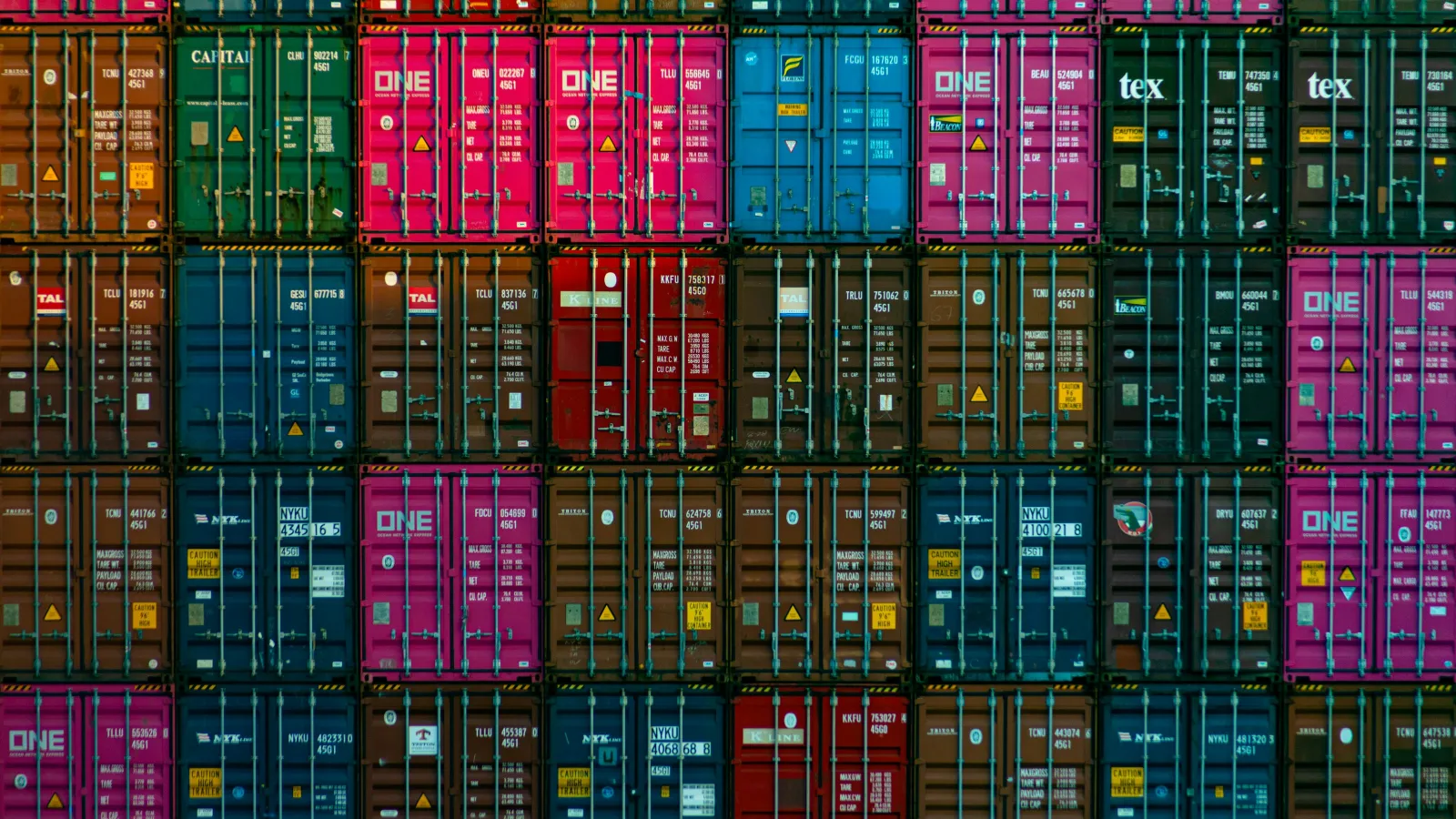 Stacked colorful shipping containers in a busy port for cargo transport and logistics.