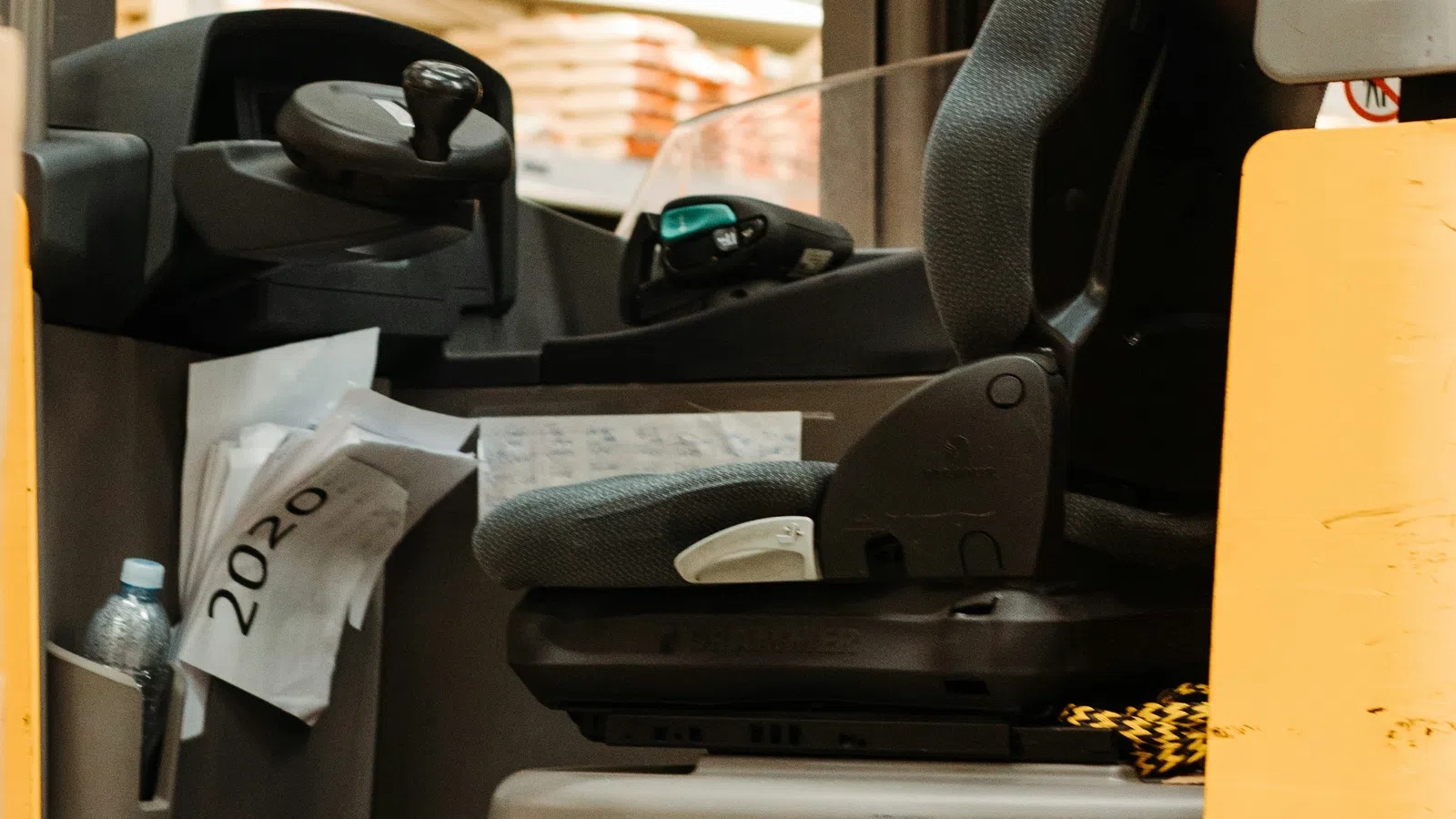 Close-up of a Jungheinrich forklift operator seat inside a warehouse with stacked goods in background.