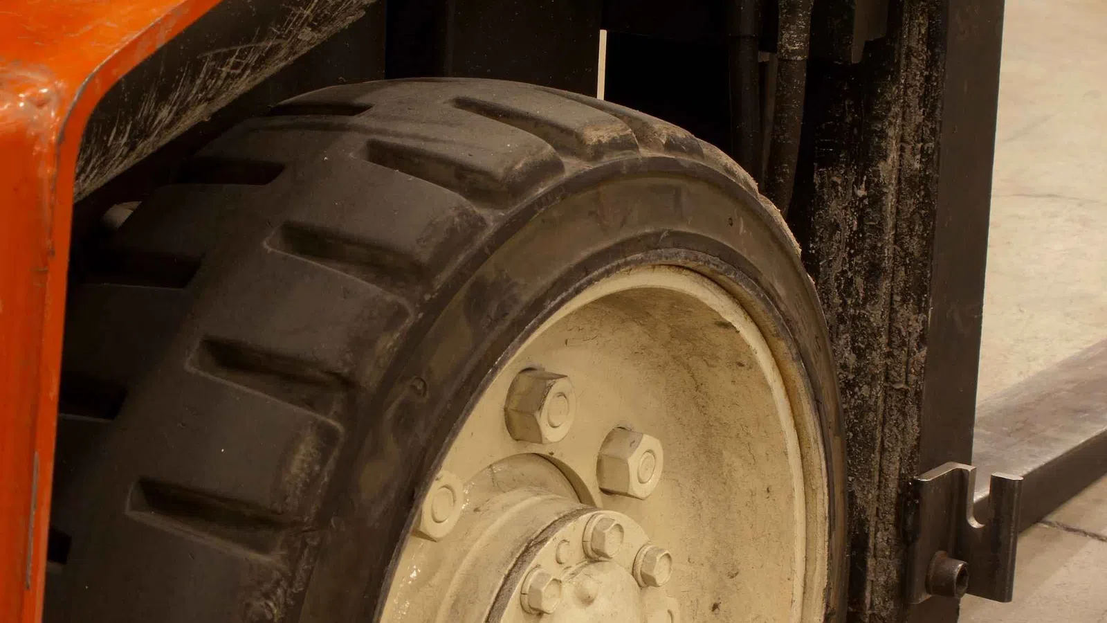 Close-up of a forklift tire and part of the lifting mechanism on a warehouse floor.