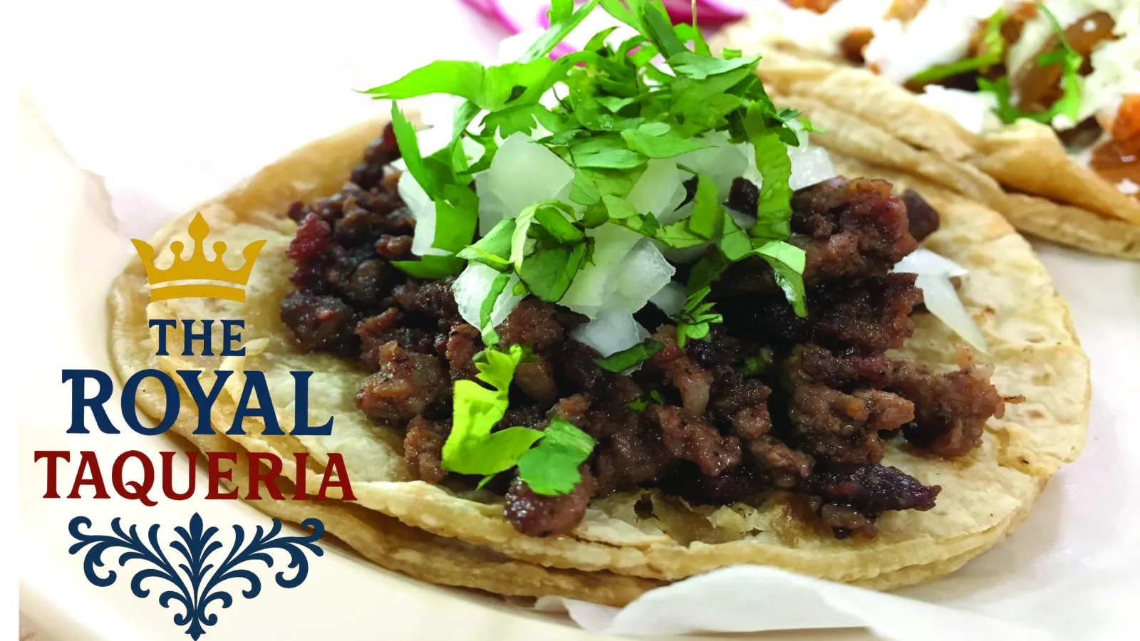 Close-up of a taco with seasoned beef, chopped onions, and fresh cilantro on a soft tortilla.