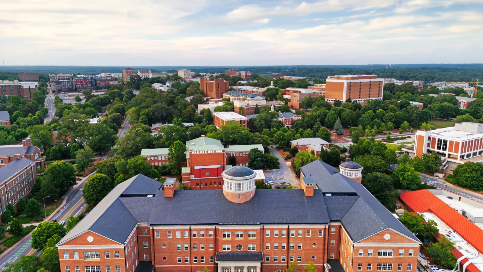 Aerial view of a large university campus with red brick buildings, greenery, and overcast sky.
