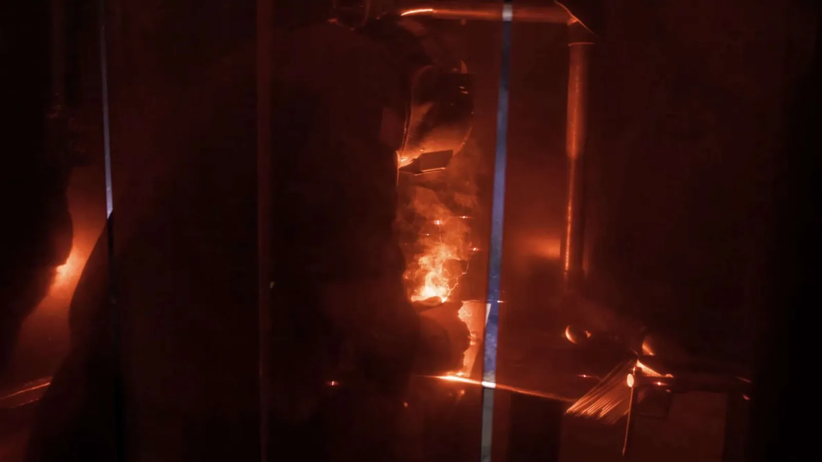Welder in protective gear working with bright sparks in a dark industrial setting