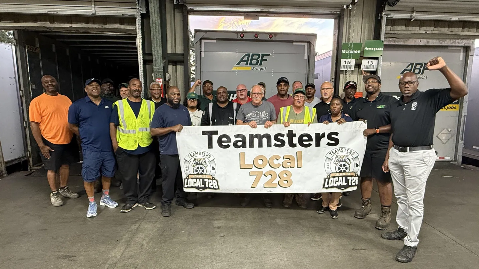 Group of workers holding a Teamsters Local 728 banner inside a warehouse loading dock area.